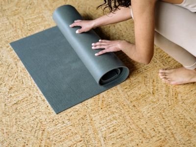 Roll of blue yoga mat on a dark gray floor.