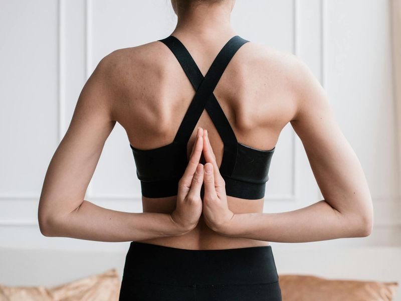 Woman practicing yoga outdoors during sunset with mountains behind.